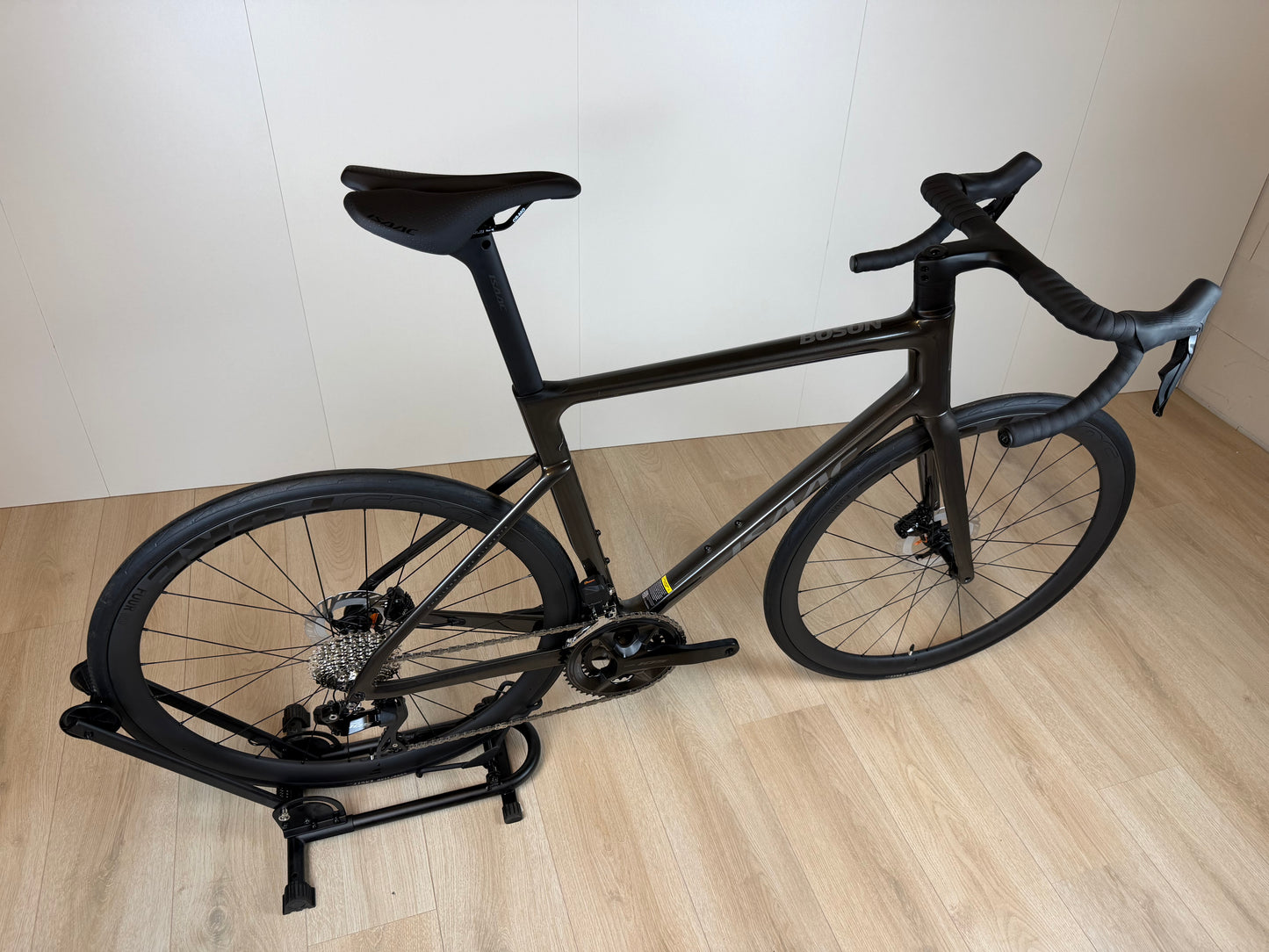 Zilveren Isaac Boson Sonic 2026 L racefiets van Vélo Studio, close-up van het frame en wiel op een weg.