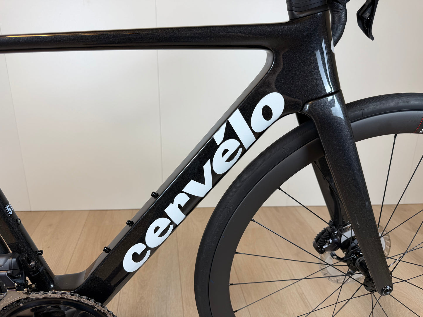 Cervélo Soloist racefiets met zwart frame en witte merknaam, aerodynamisch ontwerp, voorwiel en schijfremmen zichtbaar.