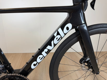 Cervélo Soloist racefiets met zwart frame en witte merknaam, aerodynamisch ontwerp, voorwiel en schijfremmen zichtbaar.