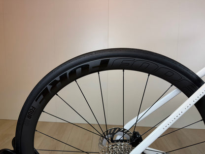 Witte Isaac Boson Mineral 2026 L racefiets van Vélo Studio, close-up van het frame en wiel.