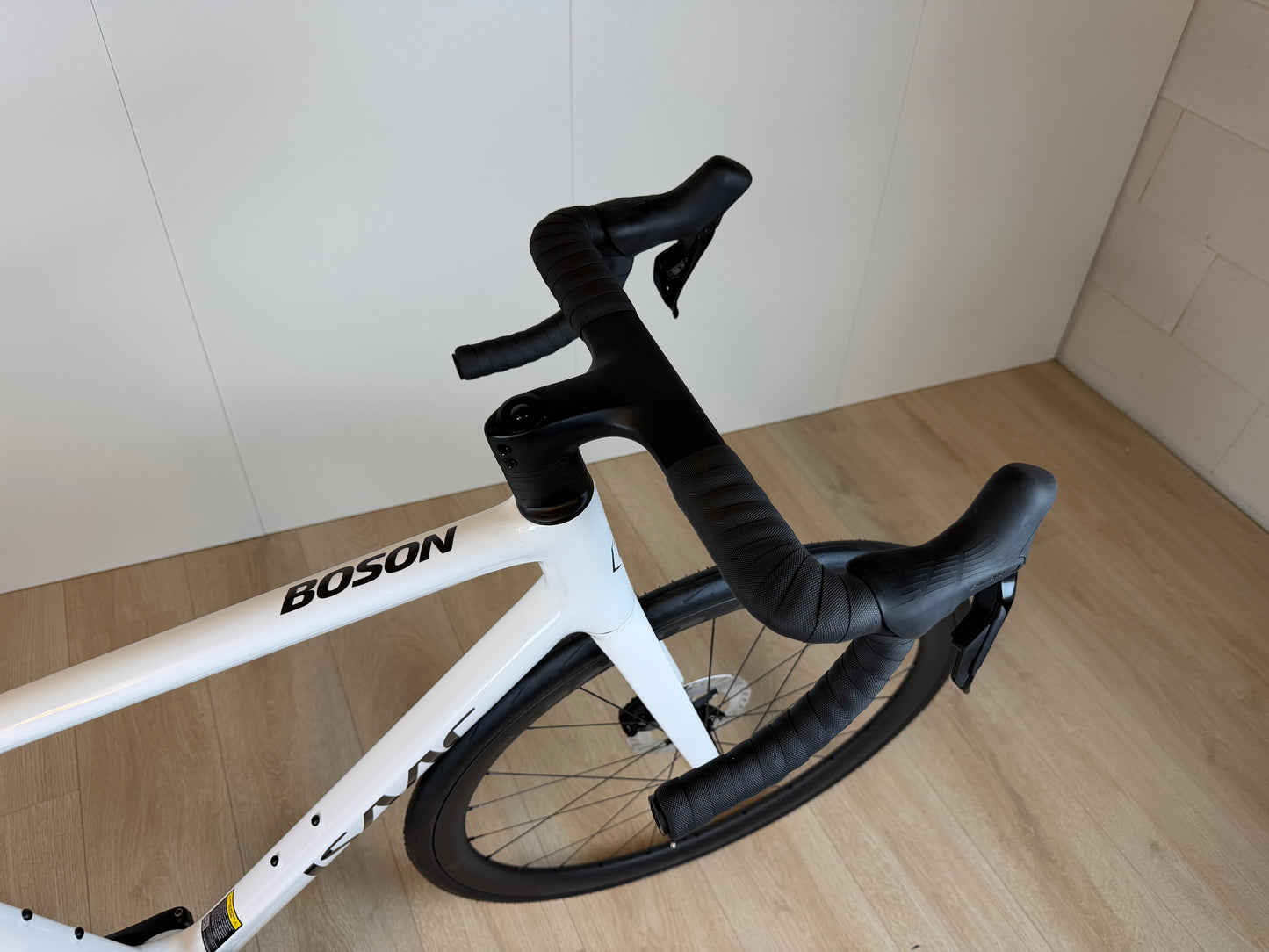 Witte Isaac Boson Mineral White 2026 M racefiets van Vélo Studio, close-up van frame en wiel aan de voorkant