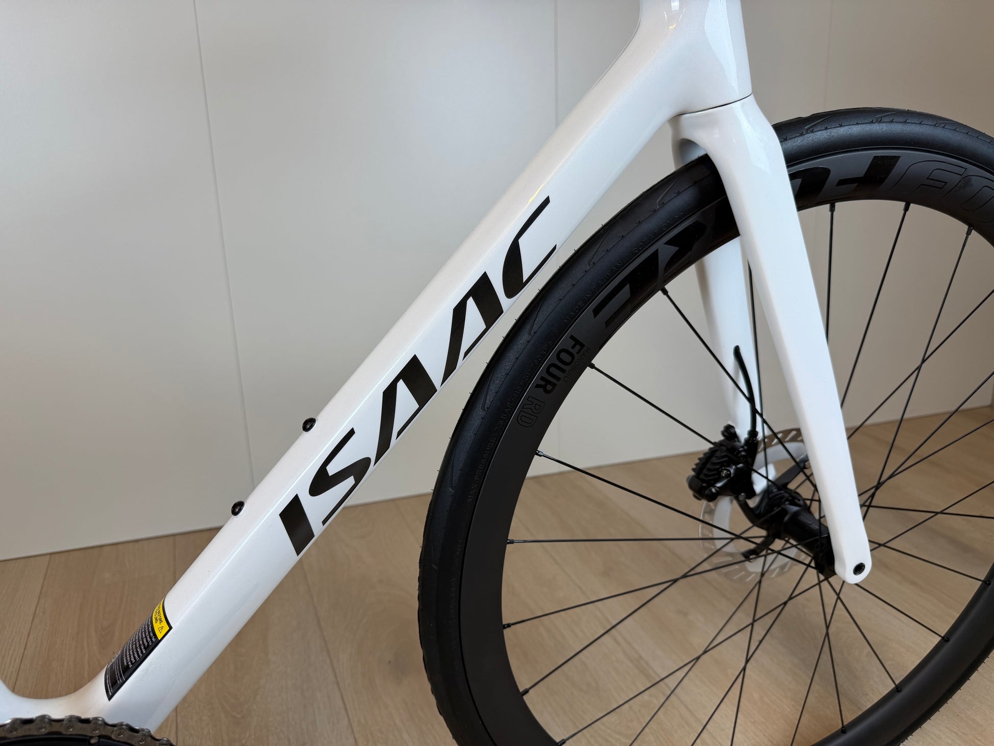 Witte Isaac Boson Mineral White 2026 M racefiets van Vélo Studio, frame en wielenset op een weg.