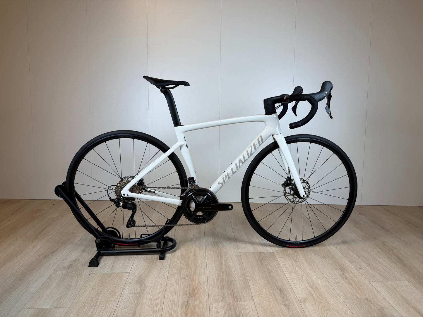Racefiets Specialized Tarmac SL7 Sport in zwart en rood, close-up van het frame en wiel, geschikt voor snelle wielerritten.