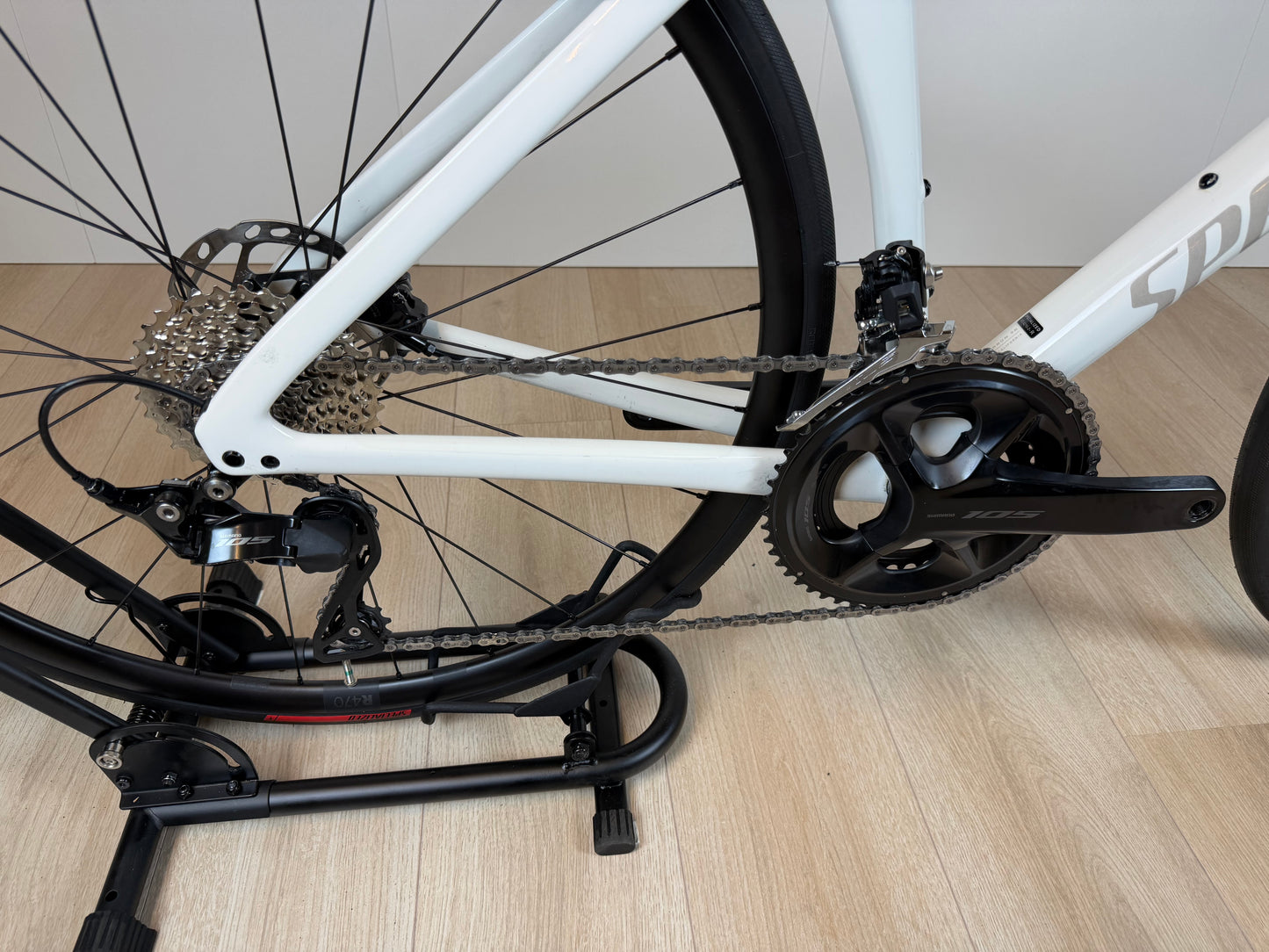 Specialized Tarmac SL7 Sport racefiets met zwart frame en aerodynamisch ontwerp, zichtbaar in een close-up van het logo en frame.