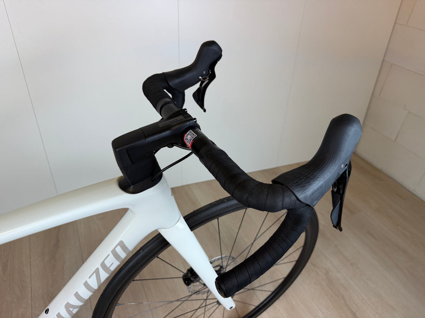 Racefiets Specialized Tarmac SL7 Sport van Vélo Studio, close-up van het frame en wiel, zwart met blauwe accenten.