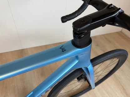 Colnago V4 racefiets met blauwe frame en zwarte stuur, zichtbaar vanaf bovenaanzicht.