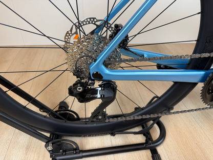 Colnago V4 racefiets frame en achterderailleur, blauw en zwart, met disc remmen en ketting op houten vloer