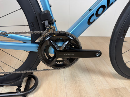 Colnago V4 racefiets frame en crankstel in lichtblauw met zwarte onderdelen, close-up van de aandrijving en wiel.