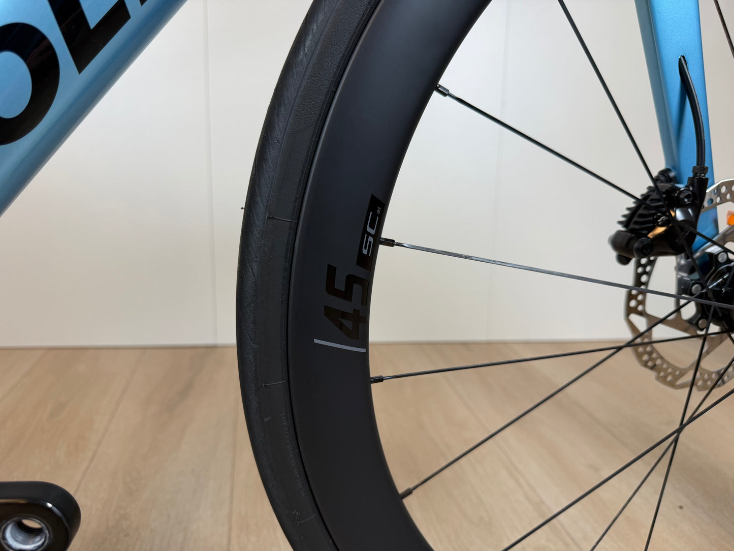 Colnago V4 racefiets met zwart wiel en blauwe frame, zichtbaar vanaf de voorzijde, binnenkant van de wiel en remmen.