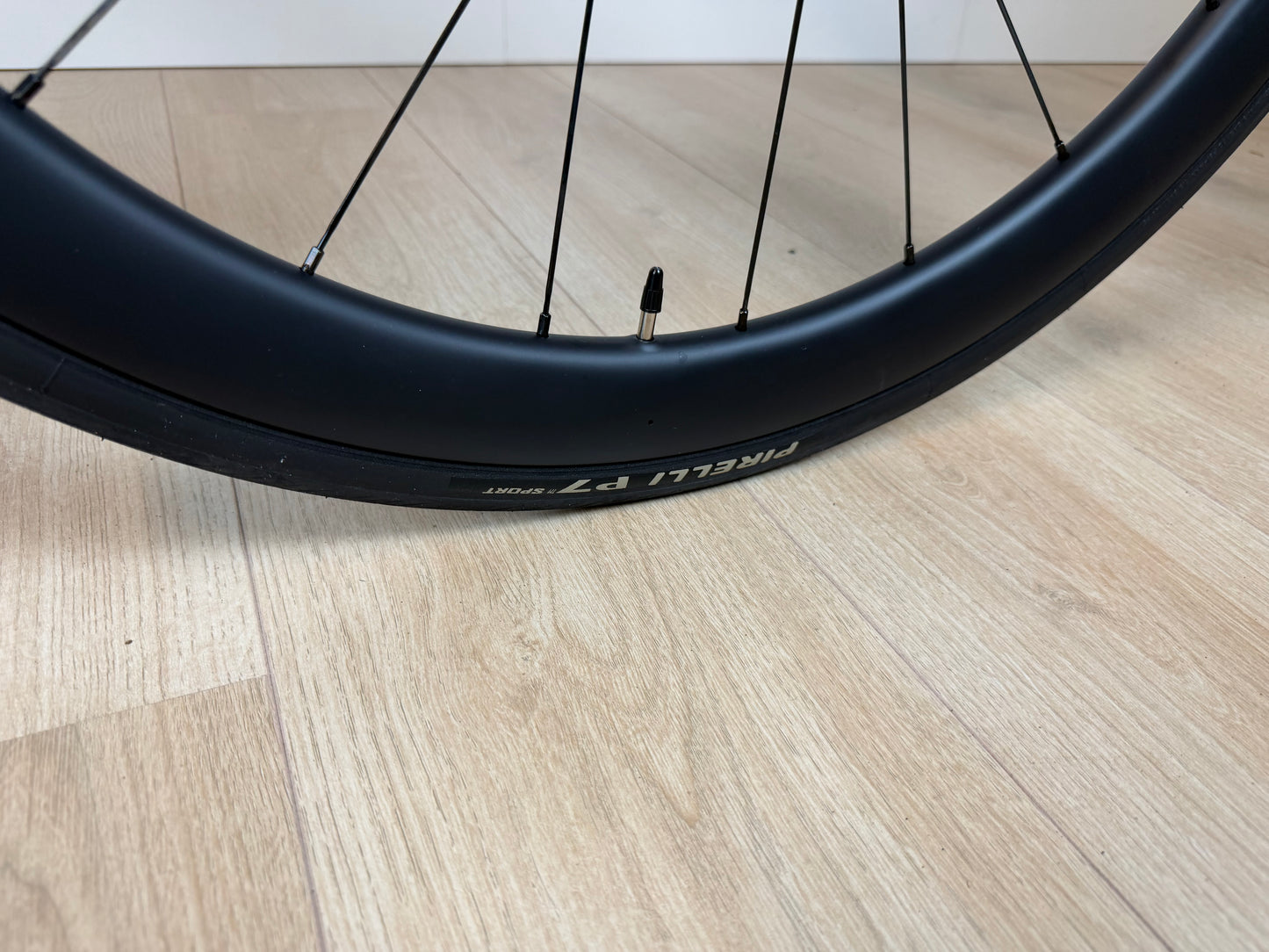 Vélo Studio Colnago V4 wiel met zwart frame en aerodynamische velg, close-up op houten vloer