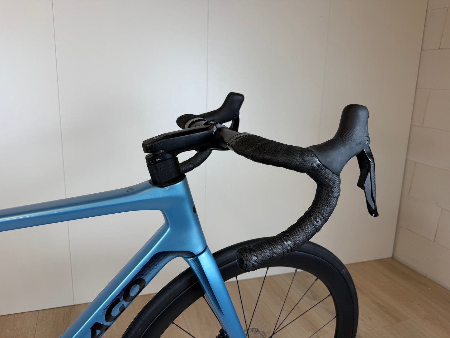 Colnago V4 racefiets met blauwe frame, zwart stuur en zadel, zijaanzicht in een binnenruimte