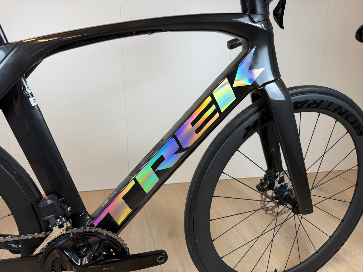 Zwart Trek Madone SL 6 racefiets met aerodynamisch frame enUltegra groepset, liggend op een witte achtergrond.