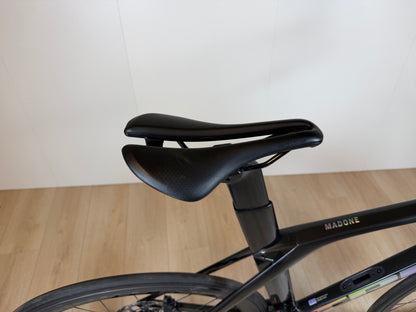 Lichtgewicht Trek Madone SL 6 racefiets met aero-frame en dunne banden, geplaatst op een weg met groene omgeving.