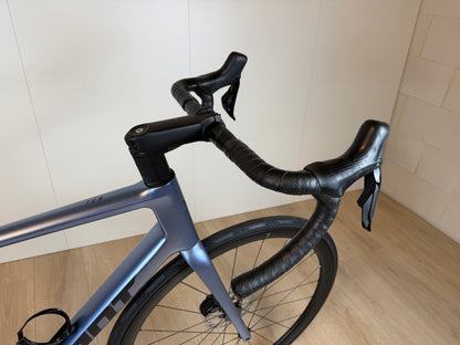 Zwarte Giant TCR Advanced 0 racefiets met aerodynamisch frame en dunne banden, op een fietsenwinkel vloer.