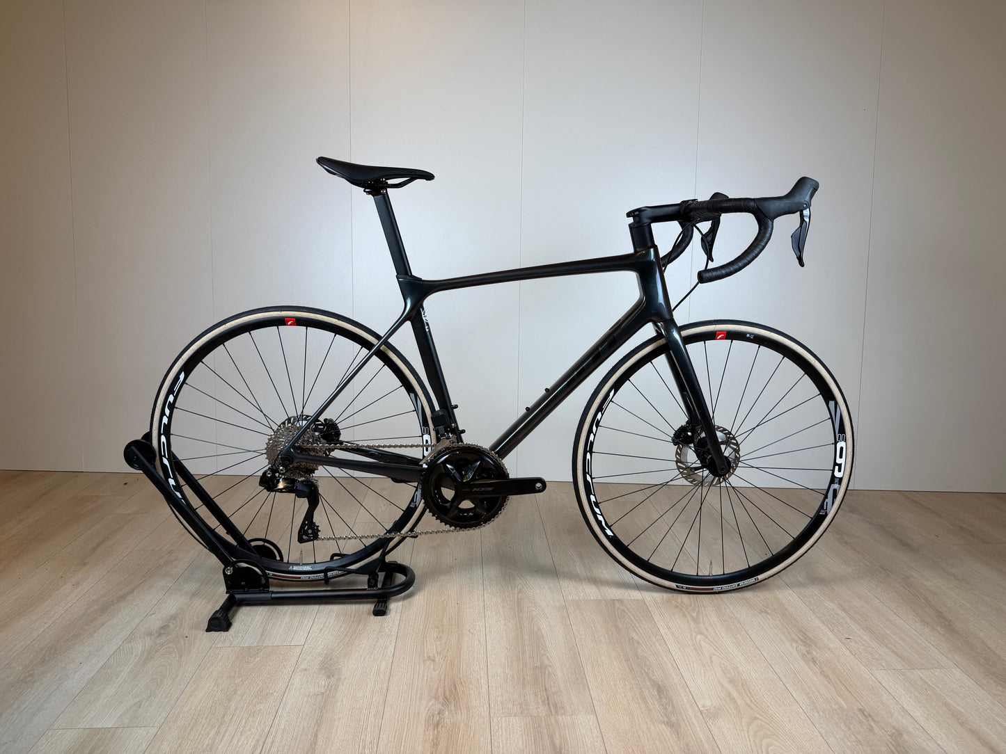 Giant TCR Pro racefiets van Vélo Studio, zwart met rode accenten, zichtbaar vanuit een zijaanzicht op een weg.