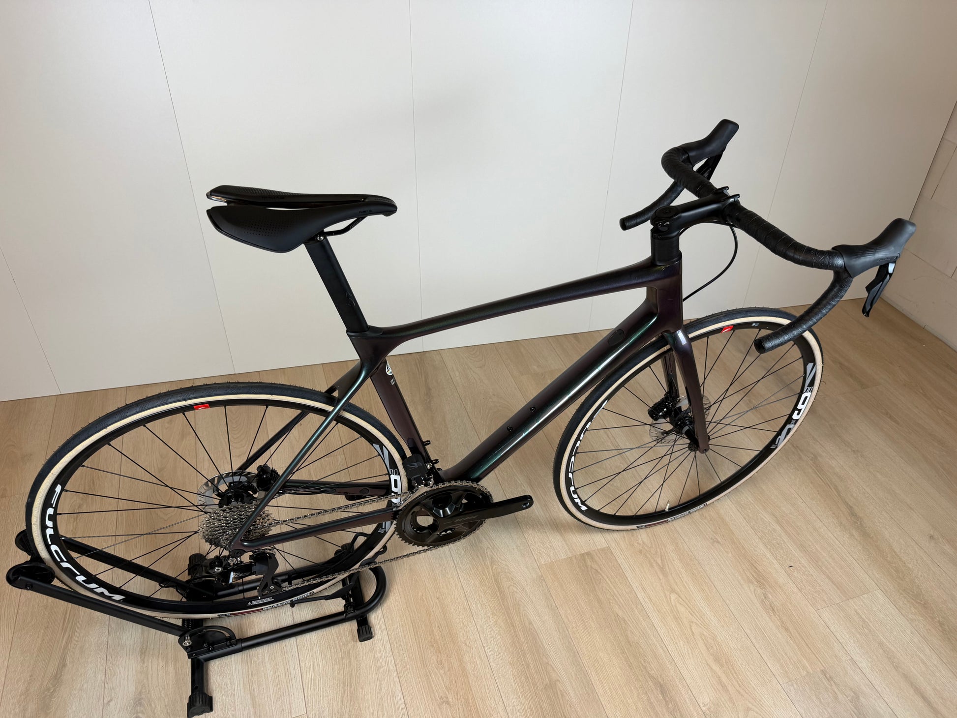 Zwart Giant TCR Pro racefiets met aerodynamisch frame en slanke velg, liggend op de grond met fietspedaal zichtbaar.