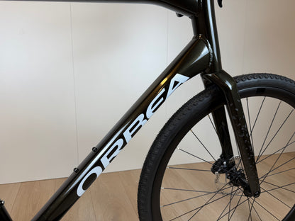 Orbea Terra H30 gravelbike met zwarte frame en dikke banden, geschikt voor off-road en wegen, zichtbaar in de afbeelding.