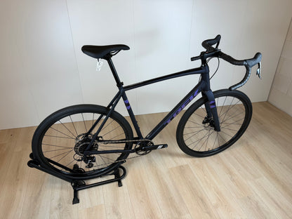 Fiets Trek Checkpoint ALR 4 van Vélo Studio, close-up van het frame en banden op een asfaltweg.