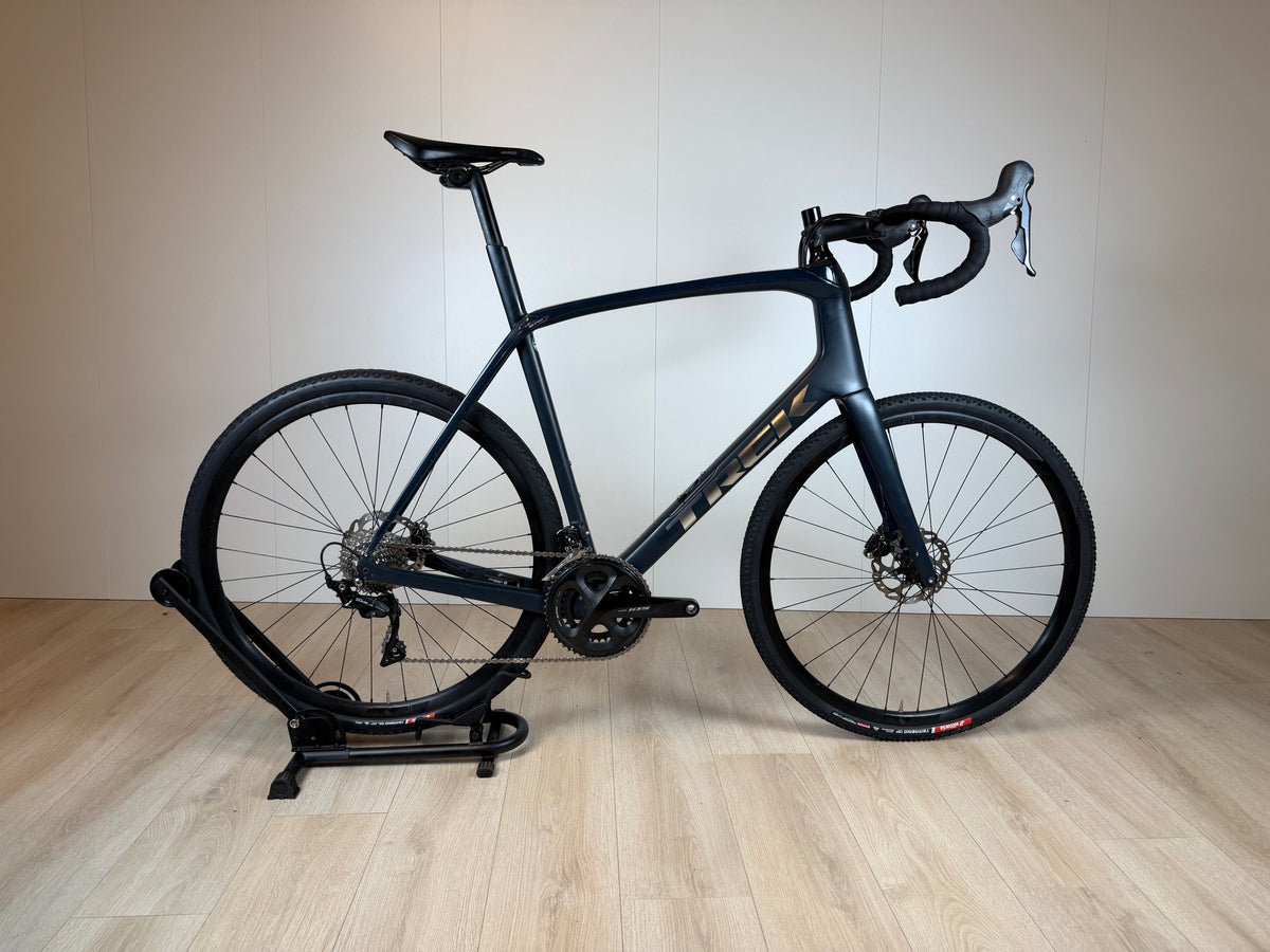 Zwart Trek Domane SL5 racefiets met aerodynamisch frame, schijfremmen en dunne banden, geplaatst op een witte achtergrond.