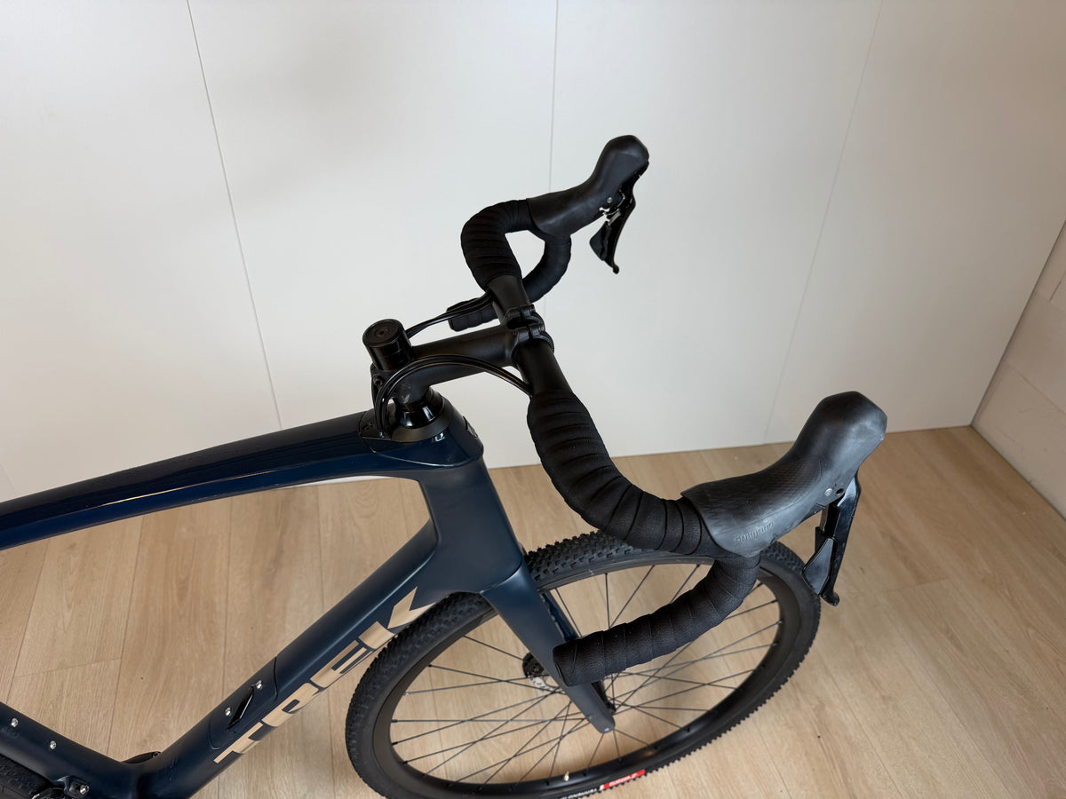 Lichte Trek Domane SL5 racefiets met zwarte frame en dunne banden, klaar voor snelheid en comfort op de weg.