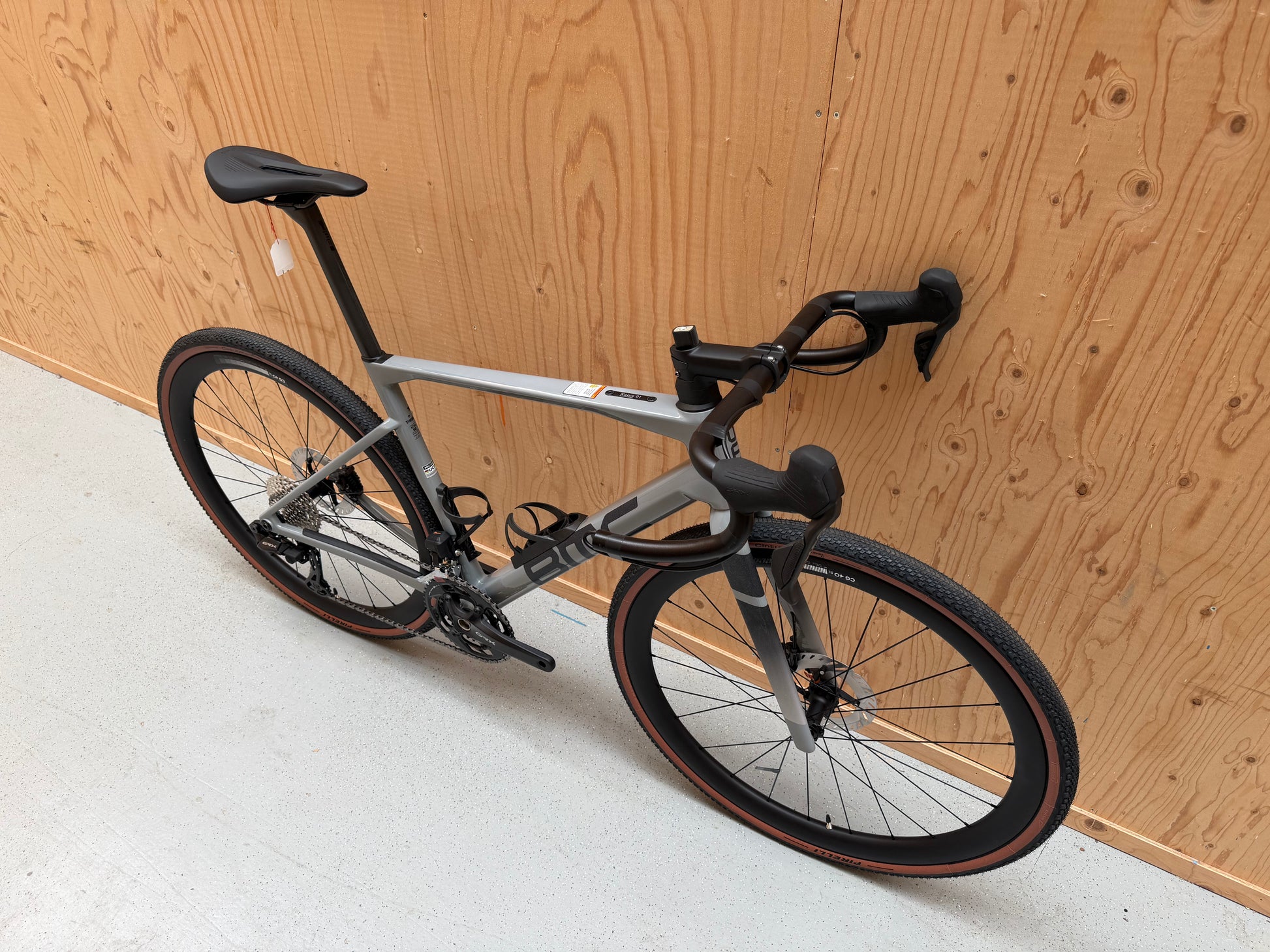 Fiets van de BMC Kaius 01 Three 2026-model, zwart en rood, met sportief frame en banden, klaar voor gebruik op de weg.