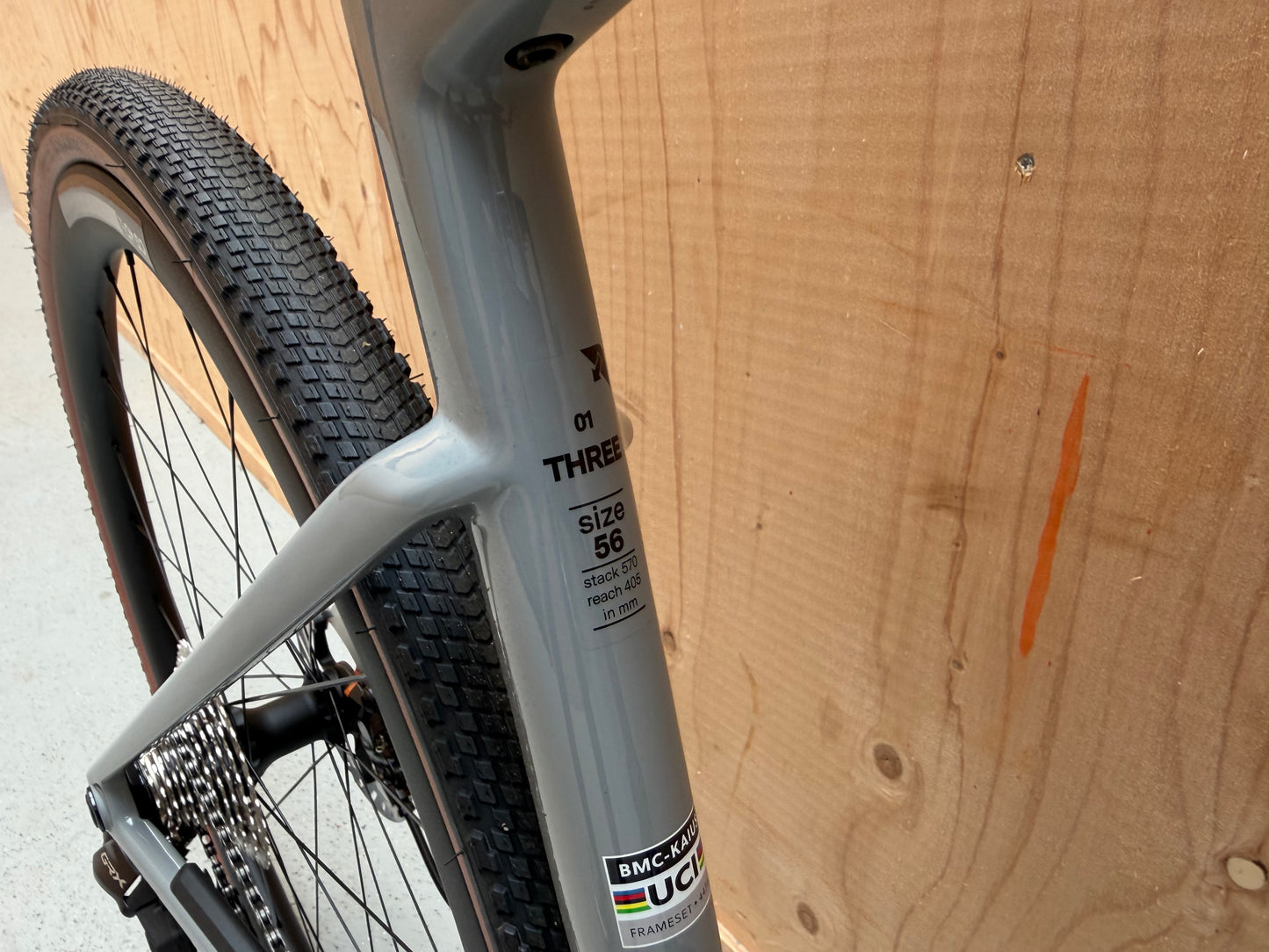 Herenfiets BMC Kaius 01 Three 2026 in zwart met blauwe accenten, frame en sportieve fietsonderdelen, klaar voor gebruik.