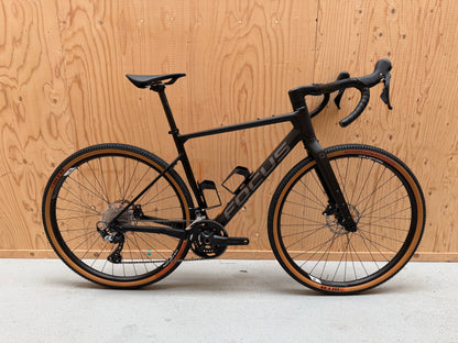 Focus Atlas 8.7 van Velostudio, close-up van het fietsframe en wiel, zwart met blauwe accenten, voor- en zijaanzicht