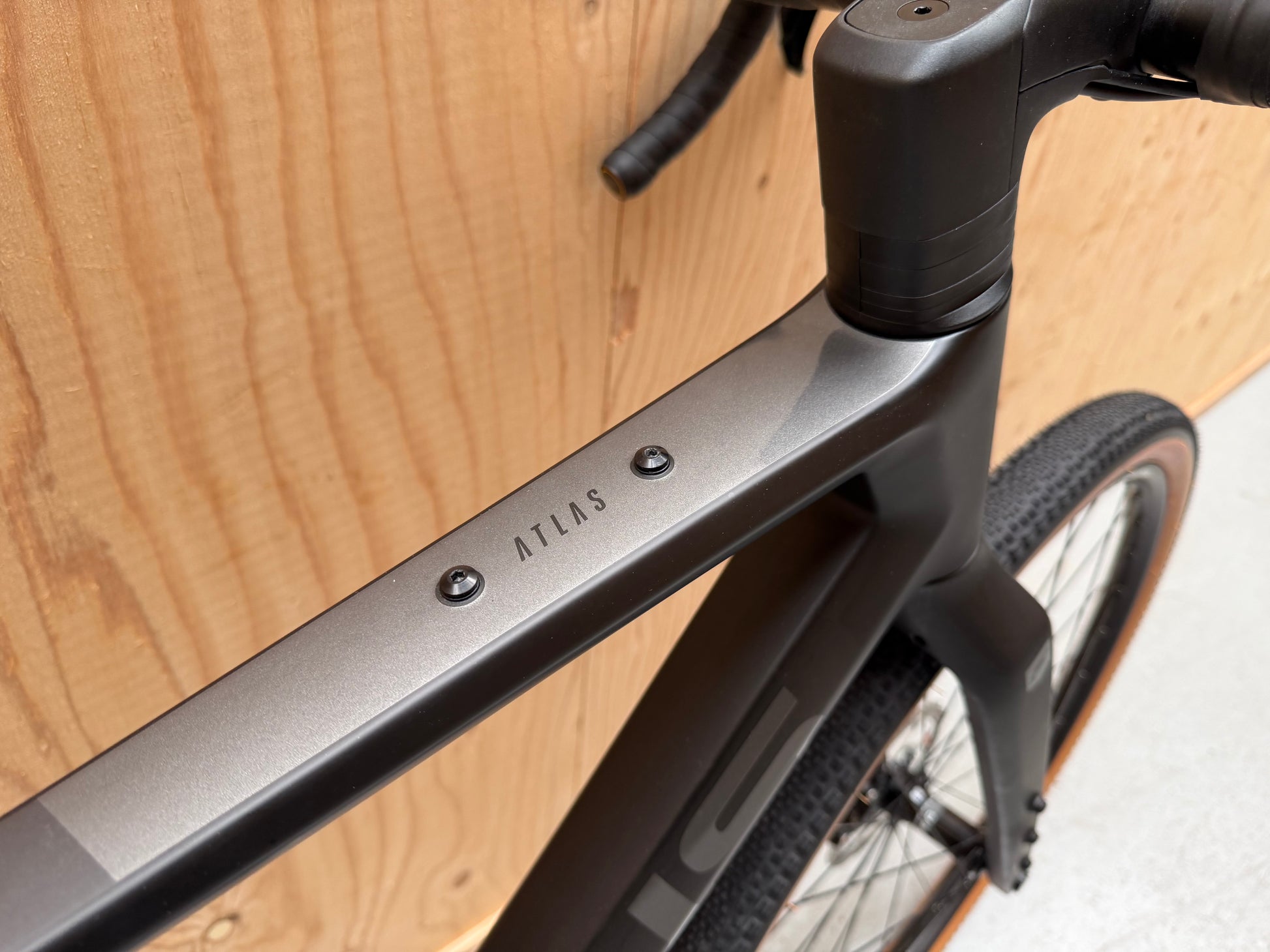 Focus Atlas 8.7 fiets van Velostudio, zwart met blauwe accenten, close-up van het frame en wiel.