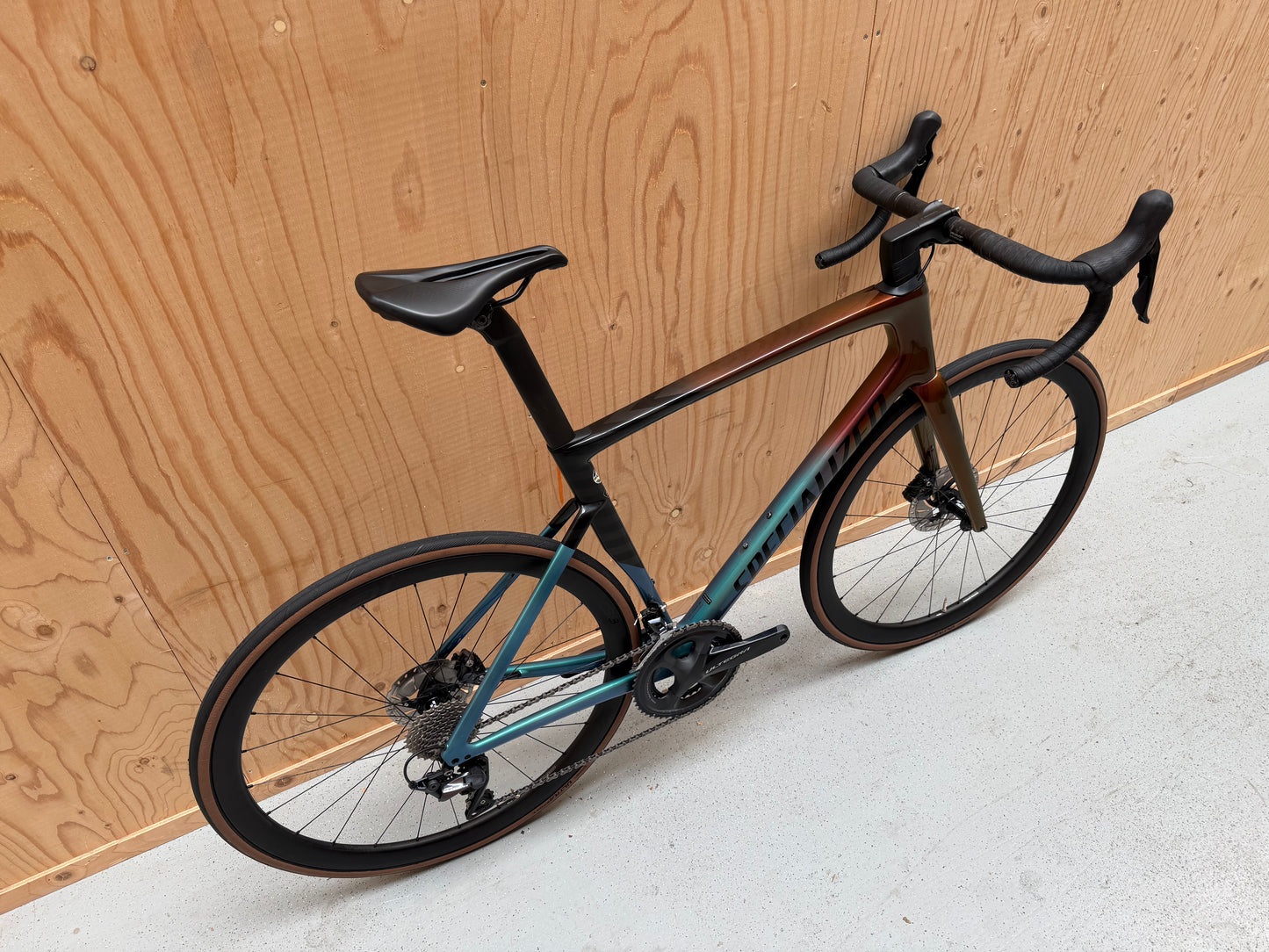 Geïllustreerde afbeelding van een Specialized Tarmac SL7 Expert racefiets met zwarte en blauwe details, weergegeven van voren en zijkant.