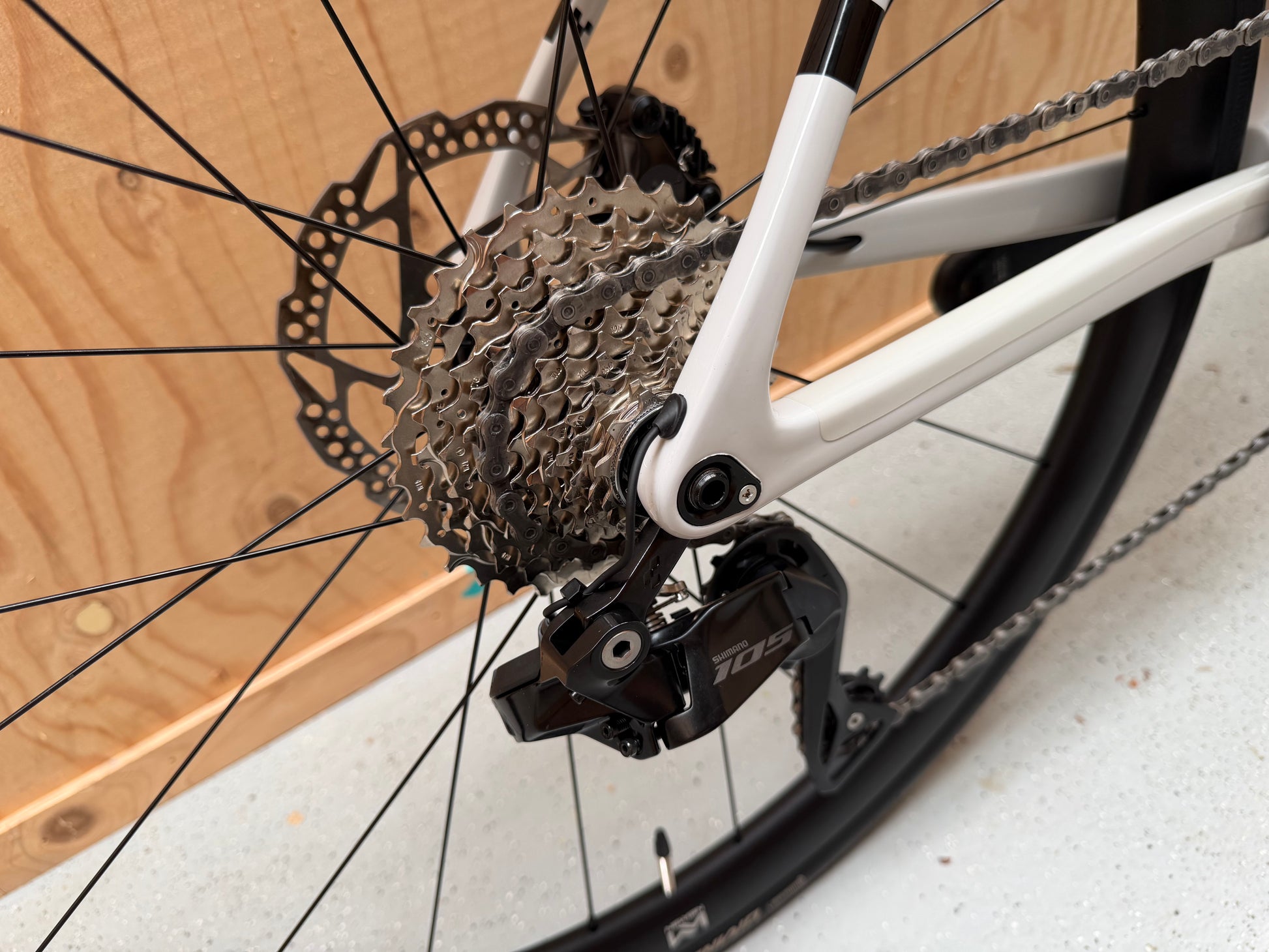 Cube Attain C:62 SLX racefiets van Velostudio, zwart met blauwe accenten, zichtbaar in zijaanzicht op een weg.