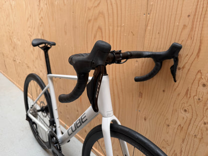 Cube Attain C:62 SLX racefiets van Velostudio, zwart met blauwe accenten, zichtbaar van voren met gedetailleerde frame en wielen
