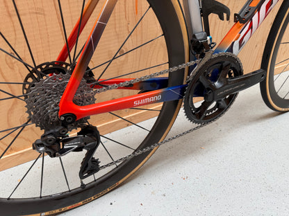 Giant Propel Advanced SL racefiets van Velostudio met Team Jacyo AlUla branding, zwart en oranje frame, close-up van de fiets.