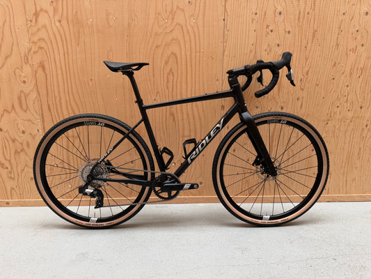Fietsfoto van de Ridley Adventure van Vélo Studio, zwart met rode accenten, klaar voor off-road avontuur op een weg.