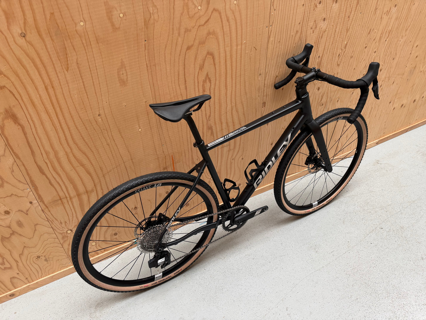 Vélo Studio Ridley Adventura racefiets met zwart frame, blauwe accenten en aerodynamisch ontwerp, klaar voor snelheid en avontuur.
