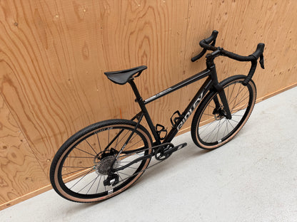 Vélo Studio Ridley Adventura racefiets met zwart frame, blauwe accenten en aerodynamisch ontwerp, klaar voor snelheid en avontuur.