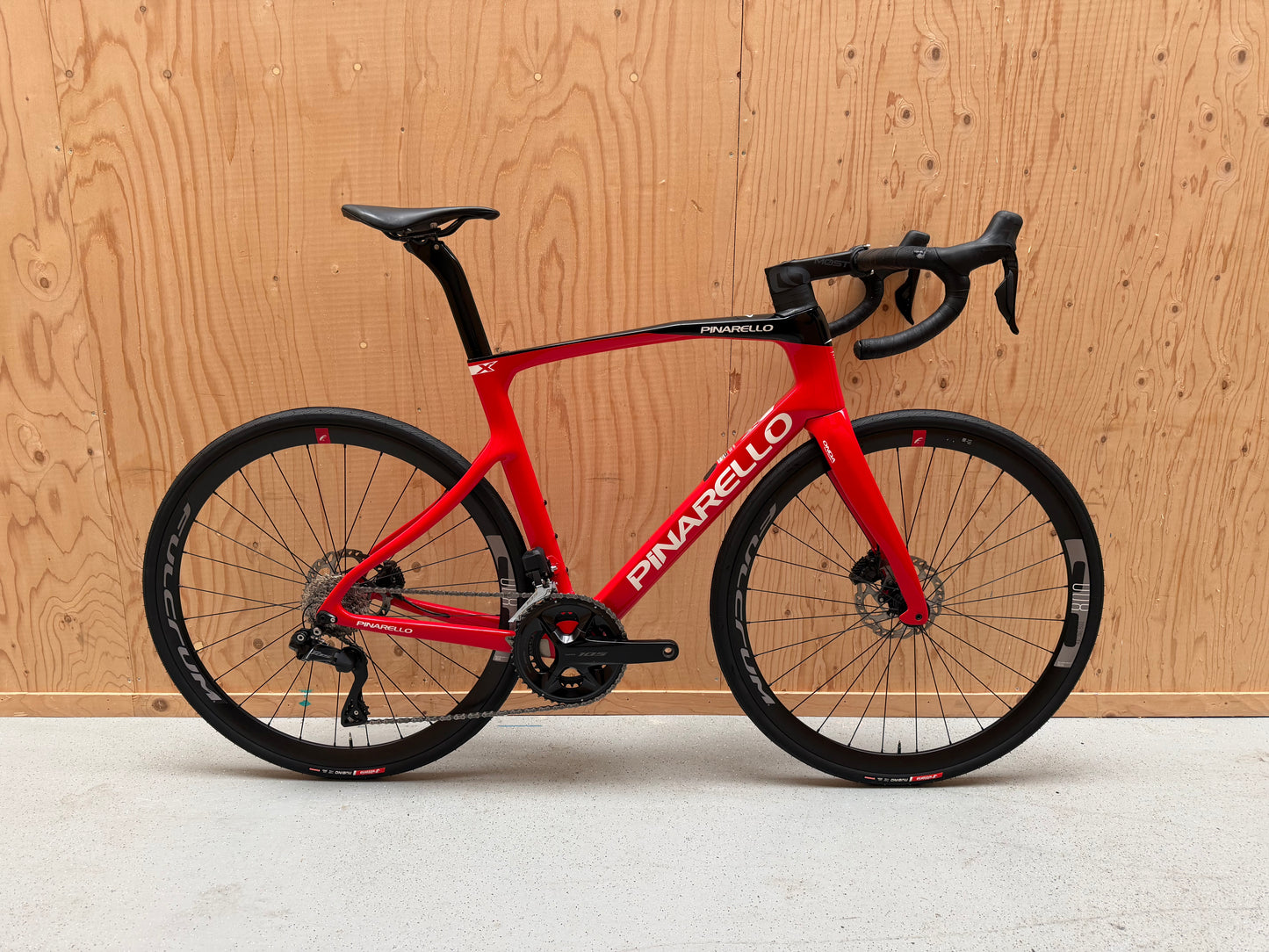 Zwarte Pinarello X3 racefiets met aerodynamisch frame en dunne banden, geplaatst op een weg.