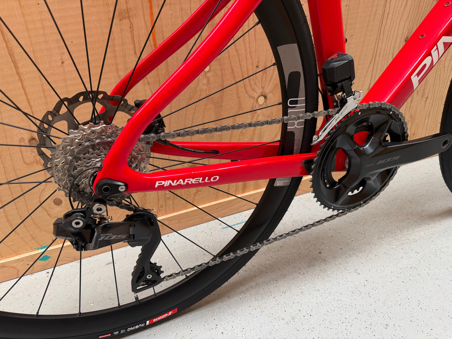 Zwart Pinarello X3 racefiets met aerodynamisch frame en dunne banden, geplaatst op een weg.