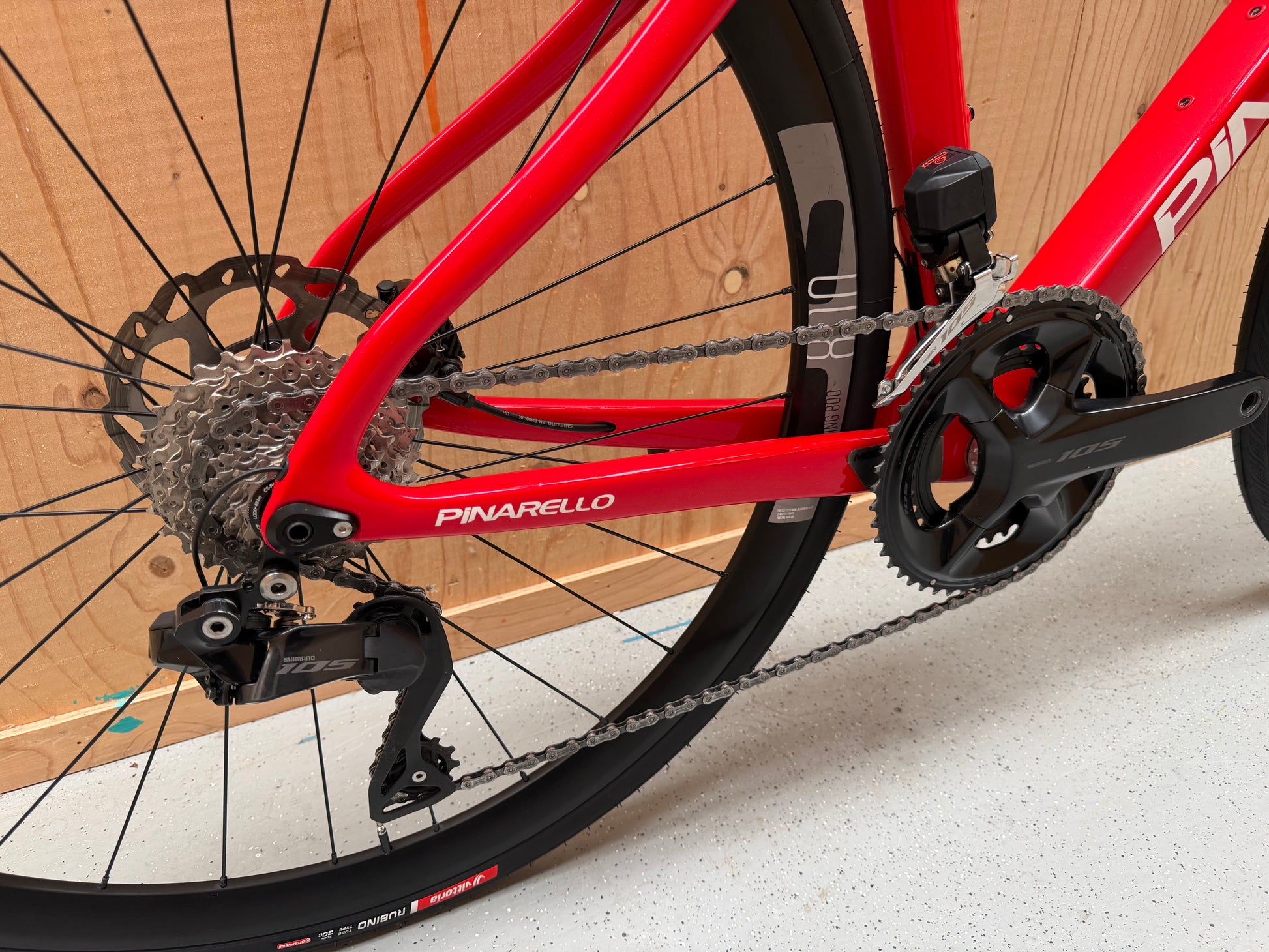 Zwart Pinarello X3 racefiets met aerodynamisch frame en dunne banden, geplaatst op een weg.