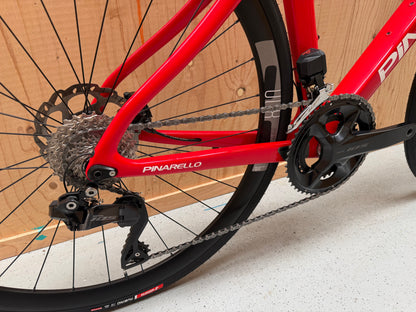 Zwart Pinarello X3 racefiets met aerodynamisch frame en dunne banden, geplaatst op een weg.